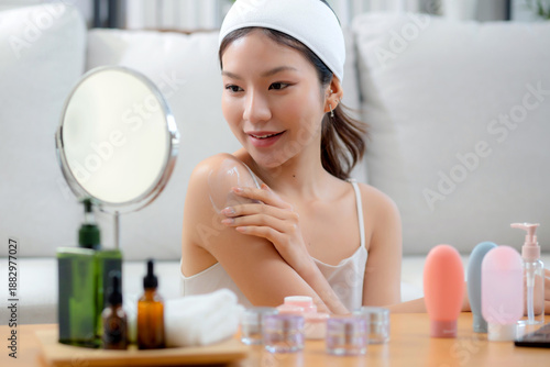 Wallpaper Mural Beauty young asian woman applying cream or lotion while looking mirror in living room at home, happy beautiful woman applying skincare for rejuvenation on shoulder, skin care and health, self care. Torontodigital.ca