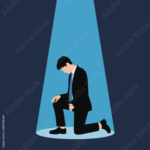 A man in a suit kneels in a bright blue spotlight with his head down Keywords: man, suit, kneeling, spotlight, blue light, dark background, despair, sadness, failure, shame