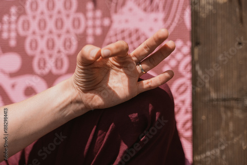 Hand Performing Yoga Gesture Against Patterned Mat