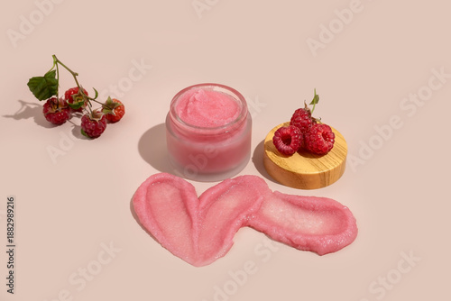jar of natural body scrub, a swatch of scrub and raspberry berries on a beige background