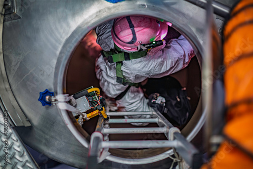 Top view male worker climb up the stairs into the tank stainless chemical