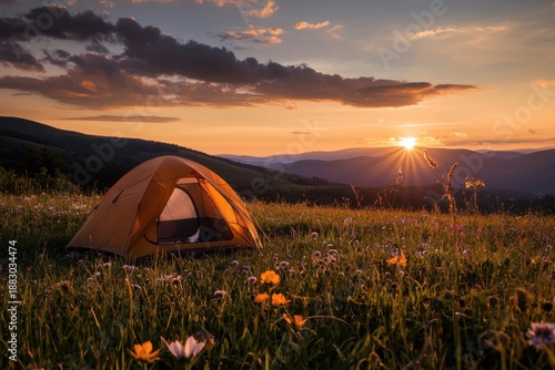 Vibrant orange tent set in wildflower meadow during warm sunset with rolling hills and dramatic clouds creating peaceful and inspiring outdoor camping scene