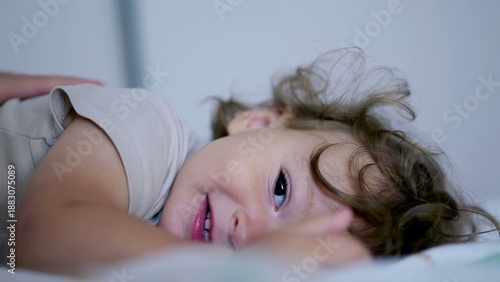 Φωτογραφία Baby lifting head while lying on bed, gazing toward camera with soft expression