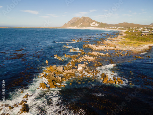 Aerial view of the rugged coastline meeting the vast ocean, with Blesberg Mountain in the distance, Betty's Bay, Western Cape, South Africa.