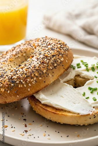 Everything Bagel with Cream Cheese and Chives on Breakfast Plate with Orange Juice and Napkin 