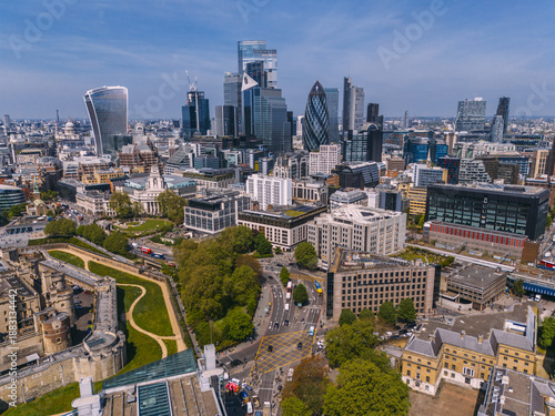 Aerial view of modern skyscrapers contrasting with the Tower of London's ancient stone, blending old and new under a bright sky, City of London, London, United Kingdom.