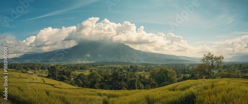 Distant green mountains under a bright blue sky, featuring expansive white clouds that evoke tranquility