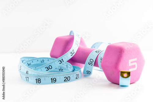 Pink dumbbell and measuring tape on a white background, symbolizing fitness and weight loss goals