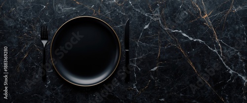 Top view of empty black gold plate, fork, and knife, black kitchen utensils on black marble table
