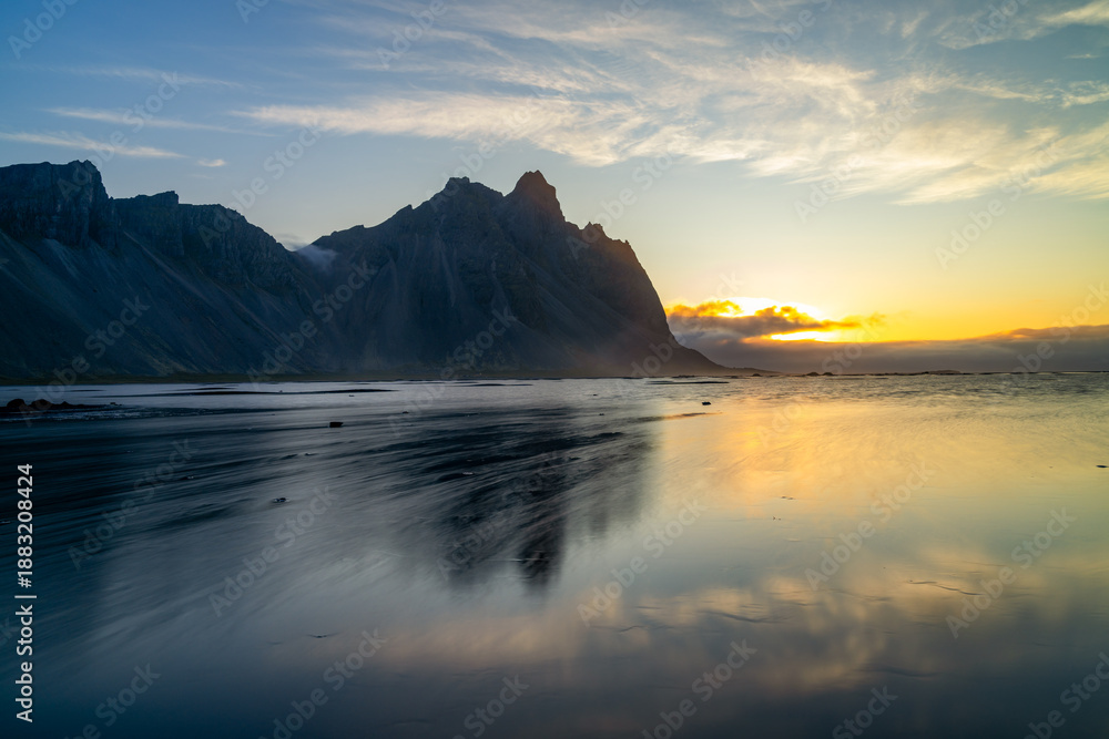 Naklejka premium view of Stokksnes beach and the iconic Vestrahorn in warm morning light with reflections in the water