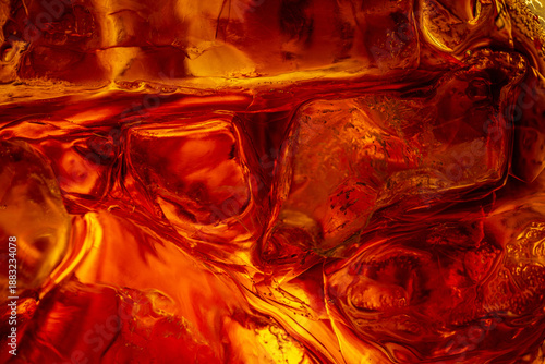 Foto Macro Close-up of Ice Cubes in Cola Drink with Golden Light,A dramatic macro close-up of ice cubes submerged in a dark amber liquid, likely cola or whiskey