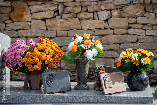 Gros bouquets de fleurs fraiches et multicolore déposés sur les tombes dans cimetière à l'occasion de la Toussaint. France. Cela rend hommage au défunt et témoigne de l'attachement et du respect.