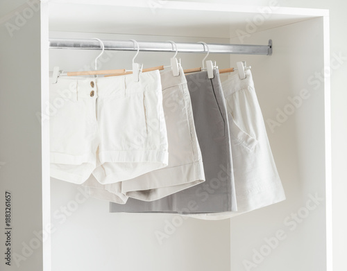 Wallpaper Mural Bright White Room with White and Gray Pleated Women Shorts Hanging on a Clothes Rail, Displayed in a White Wardrobe with a Plain Pants Hanger Torontodigital.ca