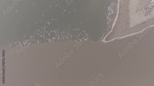 Aerial drone view of the Sangam during Magh Mela in Prayagraj. Boats move across the meeting point of the Ganga, Yamuna, and mythical Saraswati, with pilgrims gathering along the riverbanks. The scene