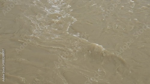 Close-up of turbulent, murky brown river water swirling rapidly during the rainy season.