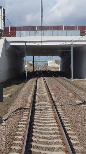 Point of view of a moving train passing through a concrete tunnel underpass on a sunny day