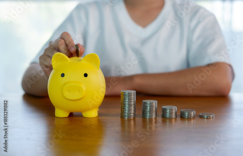 Quadro su tela Saving money concept with yellow piggy bank and stacked coins on table