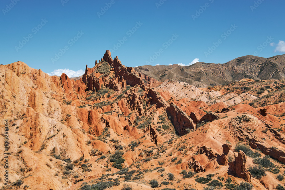 Fototapeta premium Red rock formation at Fairy Tale Canyon in Kyrgyzstan. Mountain landscape for travel and adventure concept. Outdoor desert scenery.
