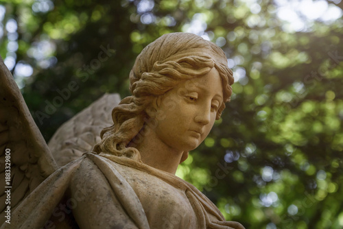 Angel with a sad face. Head in the rays of the sun. Fragment of an ancient funerary complex.