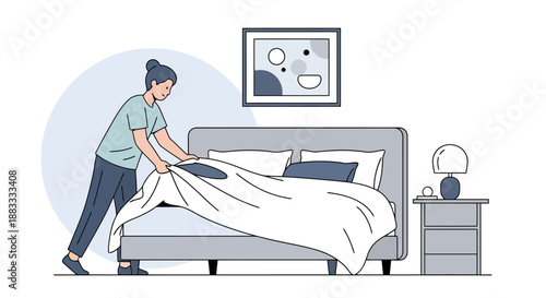 Person making a bed in a bedroom with modern furniture art on wall and nightstand lamp