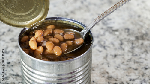 Baked beans in an open metal can with a spoon ready for serving