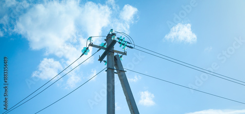 Electric cables on electric poles with a blue sky.