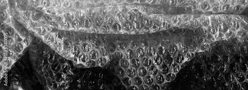 Transparent bubble wrap texture with soft reflected light. Plastic packaging material background, protective wrapping surface, abstract pattern, close up.