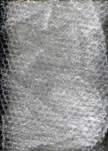 Transparent bubble wrap texture with soft reflected light. Plastic packaging material background, protective wrapping surface, abstract pattern, close up.