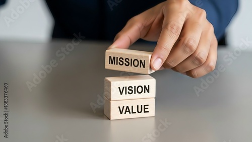 Hand stacking wooden blocks with mission, vision, and value words