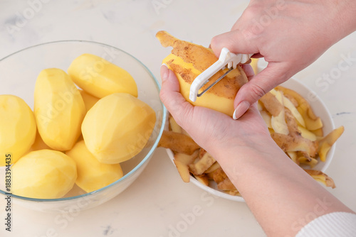 Wallpaper Mural Hands of a woman housewife peeling raw potato with a special tool knife close up, top view Torontodigital.ca