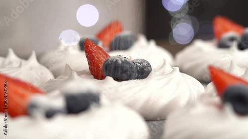 Vanilla dessert meringue with fresh berries is sprinkled with powdered sugar. Close up of sweet cake with blueberries and strawberries. Bakery confectionery