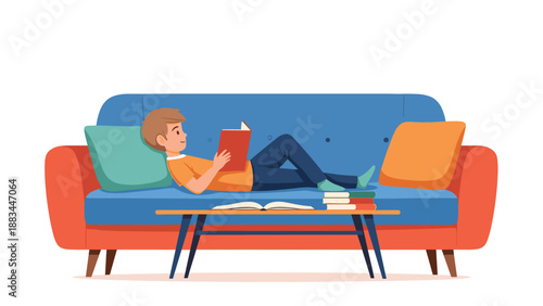 Relaxed young boy lies comfortably on a large blue sofa while reading a red book in a peaceful and cozy living room setting.