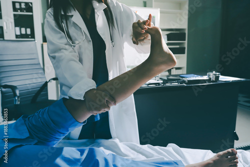 Doctor examining and supporting injured ankle of female patient in hospital room, providing medical assistance and treatment for sprain or fracture