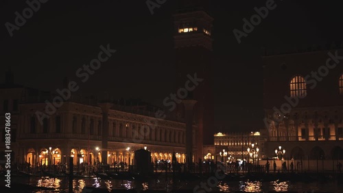 Night lights reflect on water in Venice with buildings and people nearby