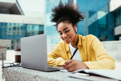 Photography Smiling Black Student Girl At Laptop Taking Notes Learning Online And Doing Homework Sitting At Modern University Building Campus Outdoor