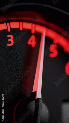 A close-up shot of a car's illuminated dashboard gauge with a red needle pointing to the number four, indicating speed or engine revolutions.