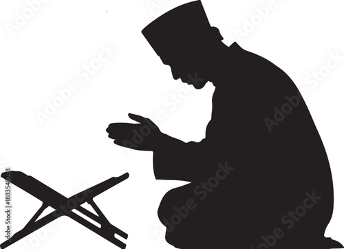 Silhouette of man praying with hands clasped near Quran stand