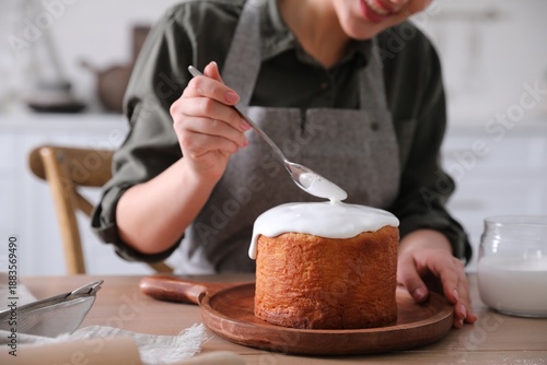 Foto Young woman decorating traditional Easter cake with glaze in kitchen, closeup