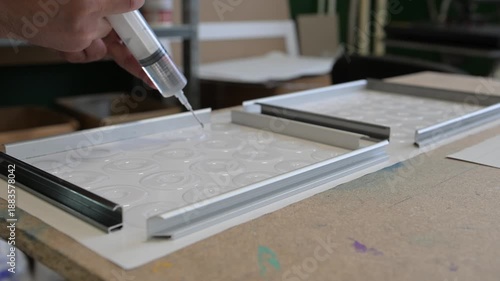 The process of pouring resin into molds for the production of souvenir products on the desktop of the printing shop