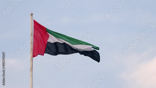 UAE flag waving in the blue sky, national symbol of UAE