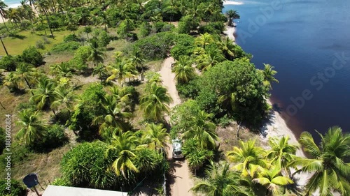 Panoramic aerial view of beaches and lagoon, with a car passing along the Bromeliad Trail, southern coast of Bahia, Maraú Peninsula, Barra Grande