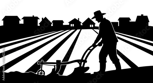 A silhouette of a man plowing a field with a tractor in a rural setting with houses in the background silhouette