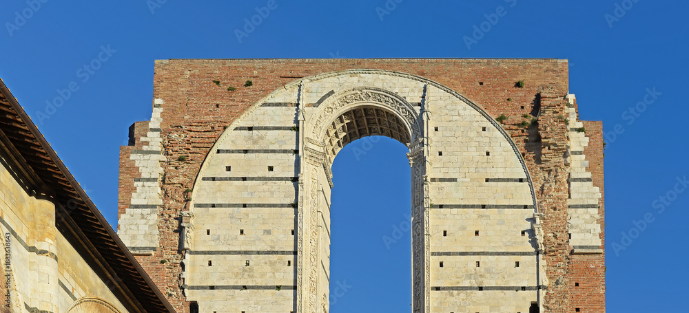 Fototapeta premium Front top gable of the 'Facciatone', a rest from the unfinished facade of the medieval cathedral or duomo of Siena with blue sky on a bright october day in Tuscany, Italy