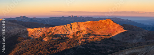 Fotografie This scenic Colorado sunrise panorama features Wander Ridge with the Continental Divide Trail cutting across its slope near Cottonwood Pass, glowing in soft orange light
