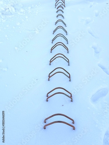 A row of metal bike racks covered in deep snow