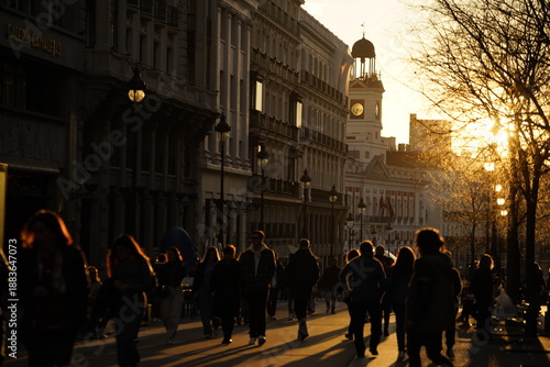 Luz de atardecer en la calle Acalá de la ciudad de Madrid con personas paseando y el foco puesto en el edificio del reloj Puerta del Sol. Madrid. España