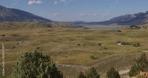 Panoramic view of Blidinje Lake surrounded by vast highland plateau, dry meadows, stone walls and Dinaric Alps mountains, Bosnia
