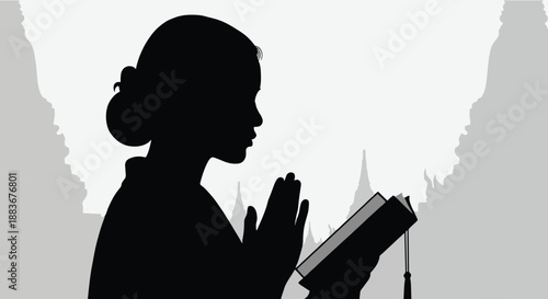 Woman praying with book in front of temple silhouette