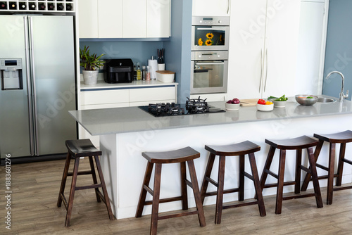Kitchen island is anchoring modern kitchen with gray stone countertop, six stools, gas cooktop