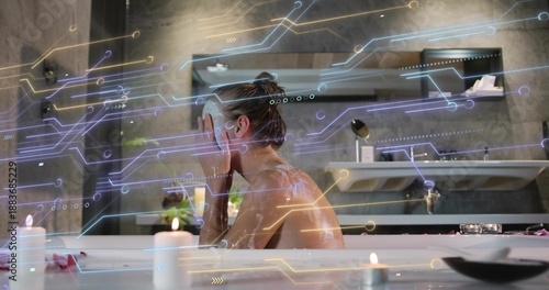 Foto Soaking woman raising hands to face in bathtub in stone bathroom, hair bun, cand